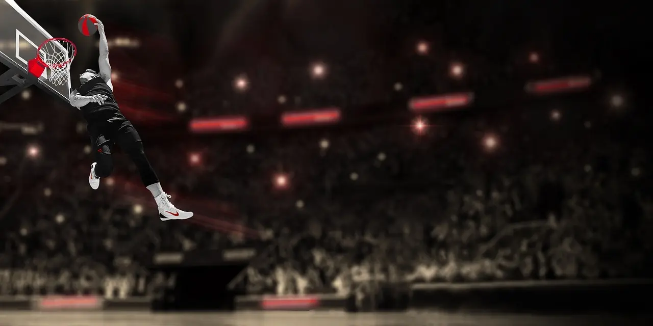 Basketballspiller der dunker foran et stadionpublikum